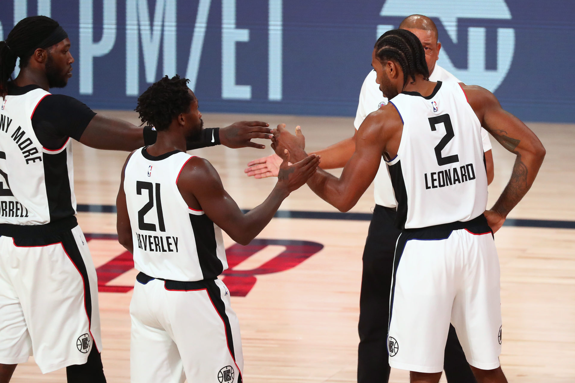 LA Clippers garde Paul George avec l'attaquant Montrezl Harrell (à gauche), le garde Patrick Beverley et l'entraîneur-chef Doc Rivers en action pendant les éliminatoires de la NBA 2020